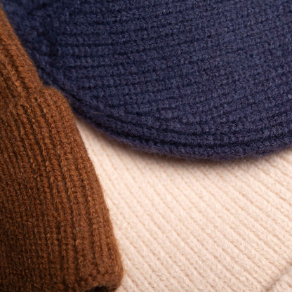 Close-up of a cozy wool knitted winter cap in a classic design, showcasing its textured pattern and soft, warm material, placed on a neutral background.